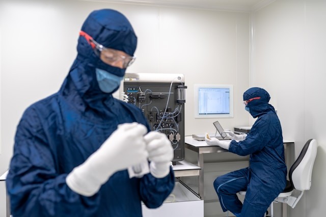 a-couple-of-people-in-blue-protective-gear-in-a-room-with-a-computer